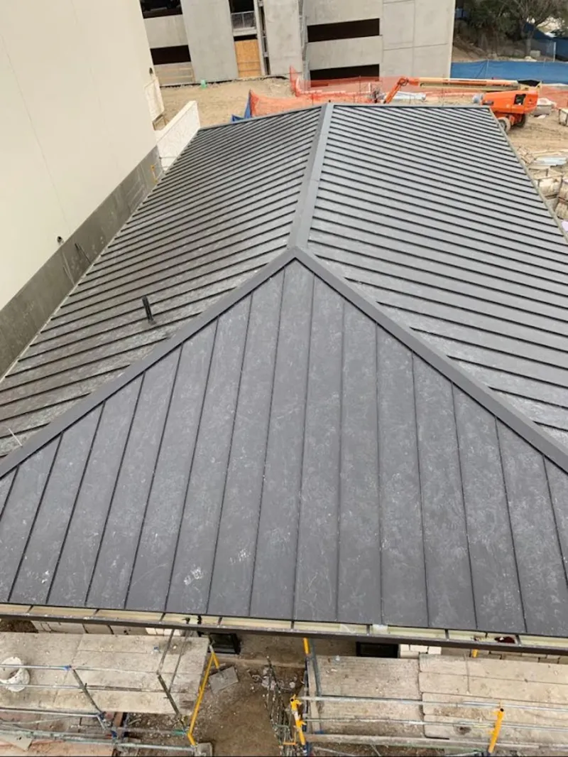 Commercial metal roof construction with crane equipment in Leawood